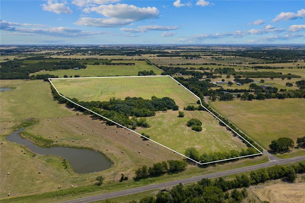 Expansive parcel featuring open fields, wooded areas, and a visible pond
