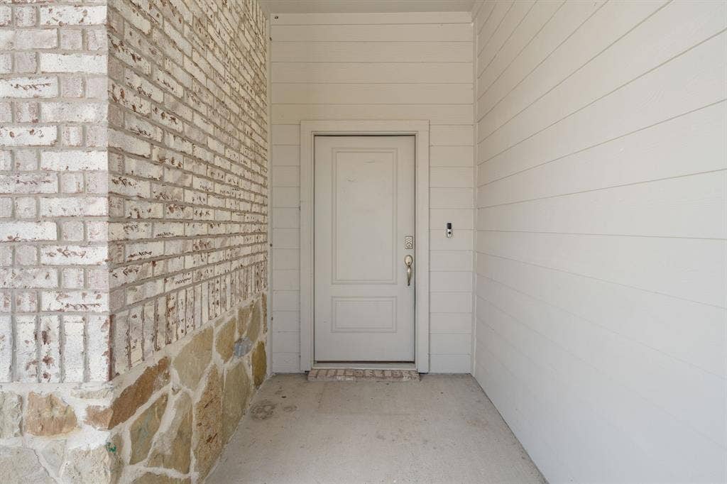 653 Bunker Hill Road, Fate, TX 75189 Front entry featuring a paneled door with a brushed nickel handle, surrounded by horizontal siding