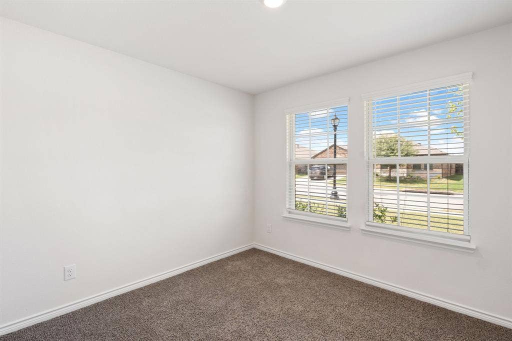 653 Bunker Hill Road, Fate, TX 75189 Room featuring two windows with white horizontal blinds, white walls, and dark gray carpet flooring