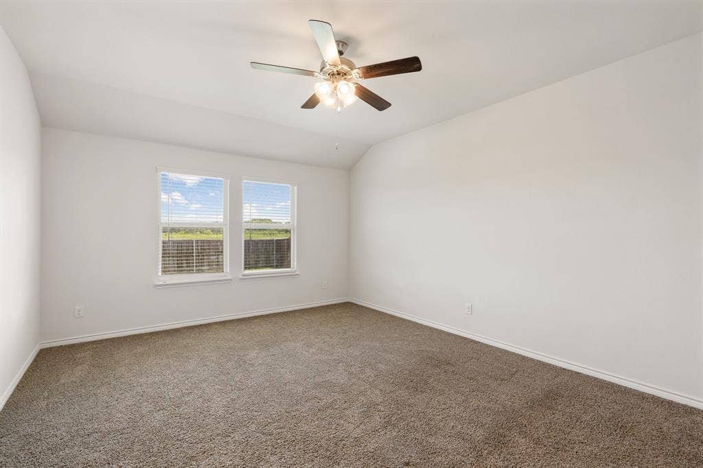 653 Bunker Hill Road, Fate, TX 75189 Spacious room featuring neutral carpet flooring, white walls, two double-hung windows with blinds, and a ceiling fan with integrated lighting