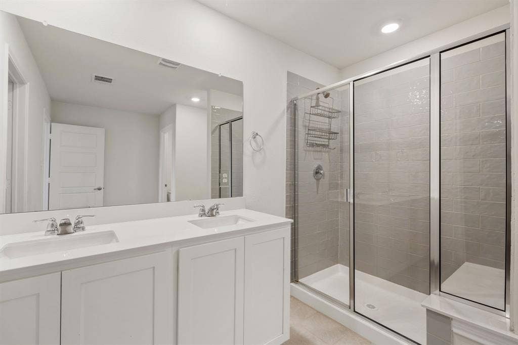 653 Bunker Hill Road, Fate, TX 75189 Contemporary bathroom featuring a spacious dual-sink vanity with white cabinetry and chrome fixtures