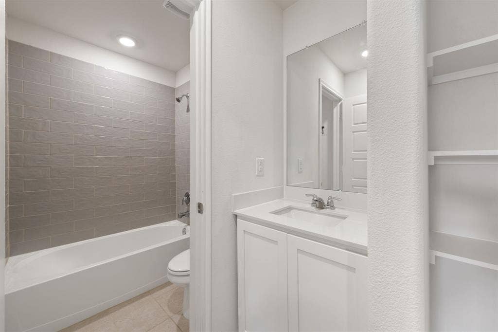 653 Bunker Hill Road, Fate, TX 75189 Bathroom featuring a white vanity with a light-toned countertop, a rectangular undermount sink, and a framed mirror