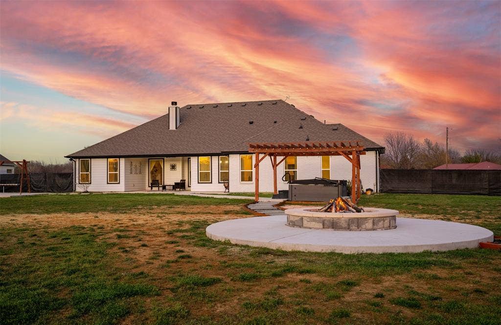 111 Bluegrass Trail, Springtown, TX 76082 Backyard with sidewalk leading to covered pergola, and firepit area with concrete decking.