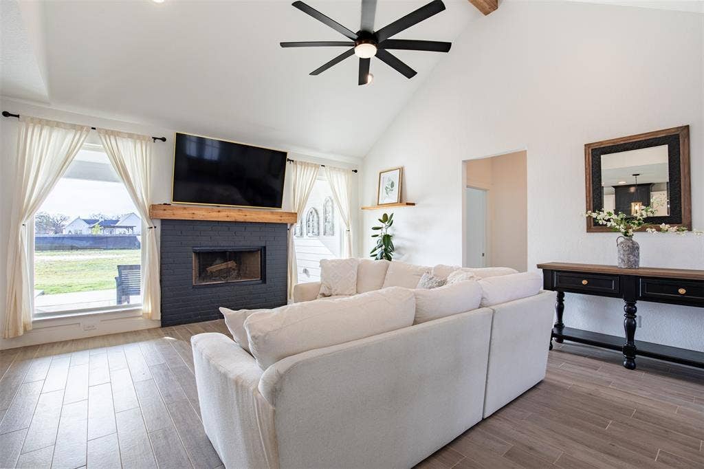 111 Bluegrass Trail, Springtown, TX 76082 Living room anchored by a wood burning fireplace and windows overlooking the covered back patio and spacious yard.