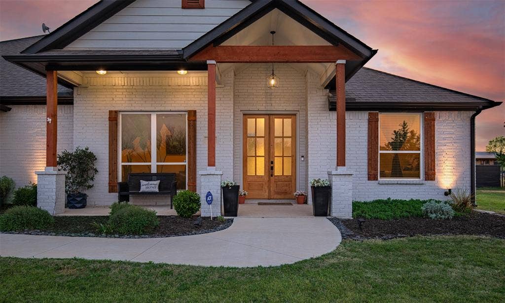 111 Bluegrass Trail, Springtown, TX 76082 Fresh mulch, landscaping, and cozy front porch with double entry door warmly welcomes you inside.
