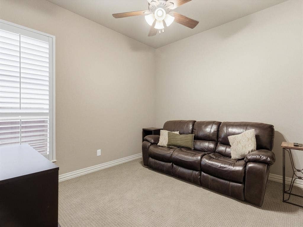 2115 N Hill Drive, Irving, TX 75038 Secondary bedroom featuring light carpet, nice closet, ceiling fan and window with plantation shutters.