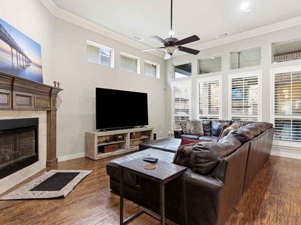 2115 N Hill Drive, Irving, TX 75038 Living area featuring ornamental molding, a ceiling fan, wood finished floors, fireplace with gas logs and healthy amount of natural light