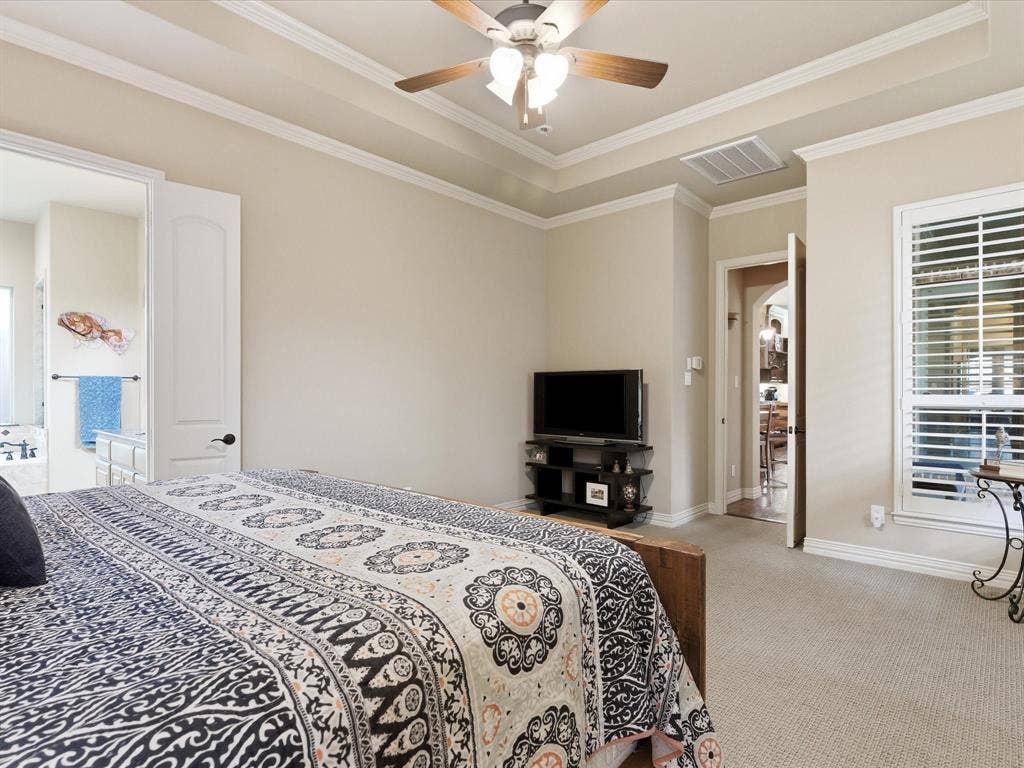 2115 N Hill Drive, Irving, TX 75038 Large primary bedroom with upgraded carpet, raised ceiling, crown molding, and ceiling fan.
