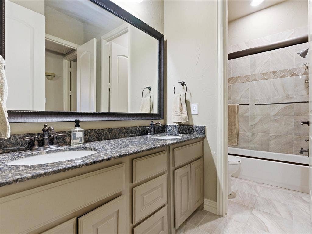 2115 N Hill Drive, Irving, TX 75038 Bathroom with double vanity, tile floors and shower / bath combination with glass door.