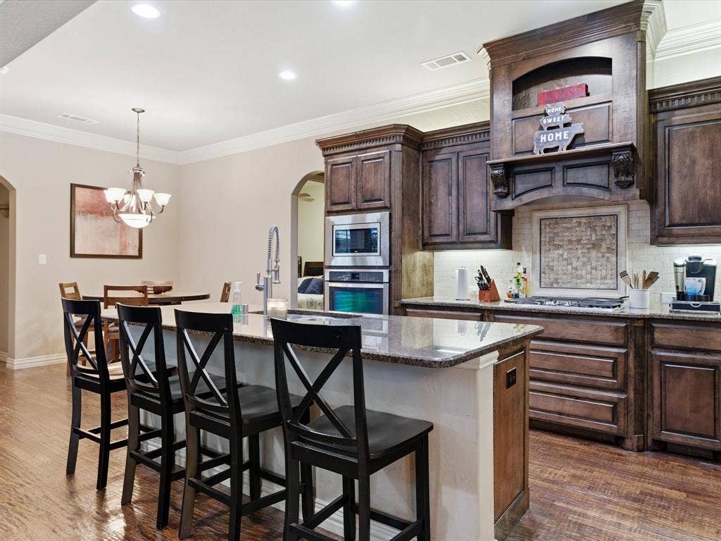 2115 N Hill Drive, Irving, TX 75038 Kitchen with arched walkways, wide hallways, ornamental molding, granite counters and travertine backsplash.