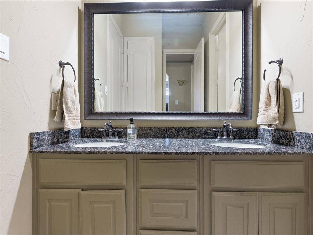 2115 N Hill Drive, Irving, TX 75038 Bathroom featuring double vanity, framed mirror, granite tops with Kohler sinks and oil rub bronze plumbing fixtures.