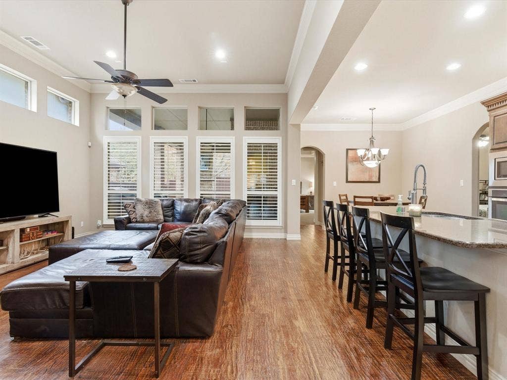 2115 N Hill Drive, Irving, TX 75038 Living area featuring arched walkways, high ceilings,wood finished floors, crown molding, a chandelier, and ceiling fan. Great natural lighting and open to the kitchen.