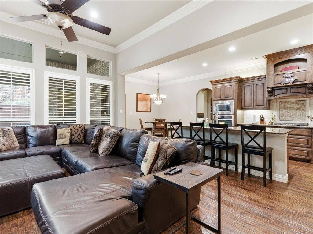 2115 N Hill Drive, Irving, TX 75038 Living room with crown molding, 3/4 inch handscraped flooring, ceiling fan, a chandelier, and arched walkways