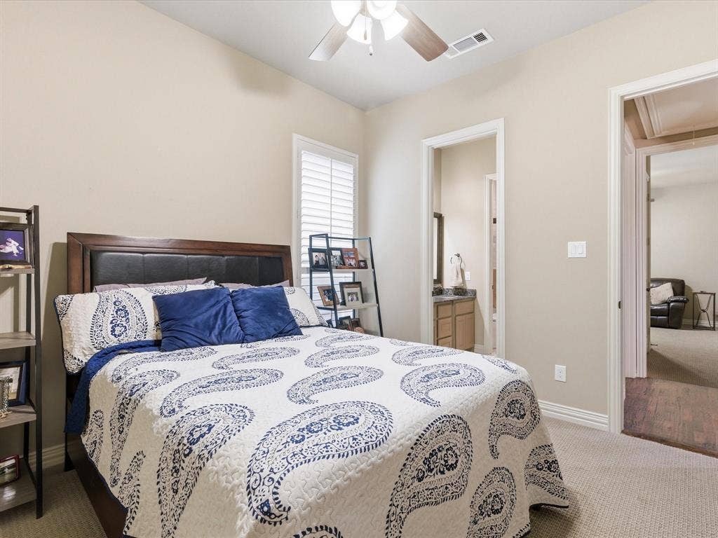 2115 N Hill Drive, Irving, TX 75038 Secondary bedroom with light colored carpet, connected bathroom, and ceiling fan