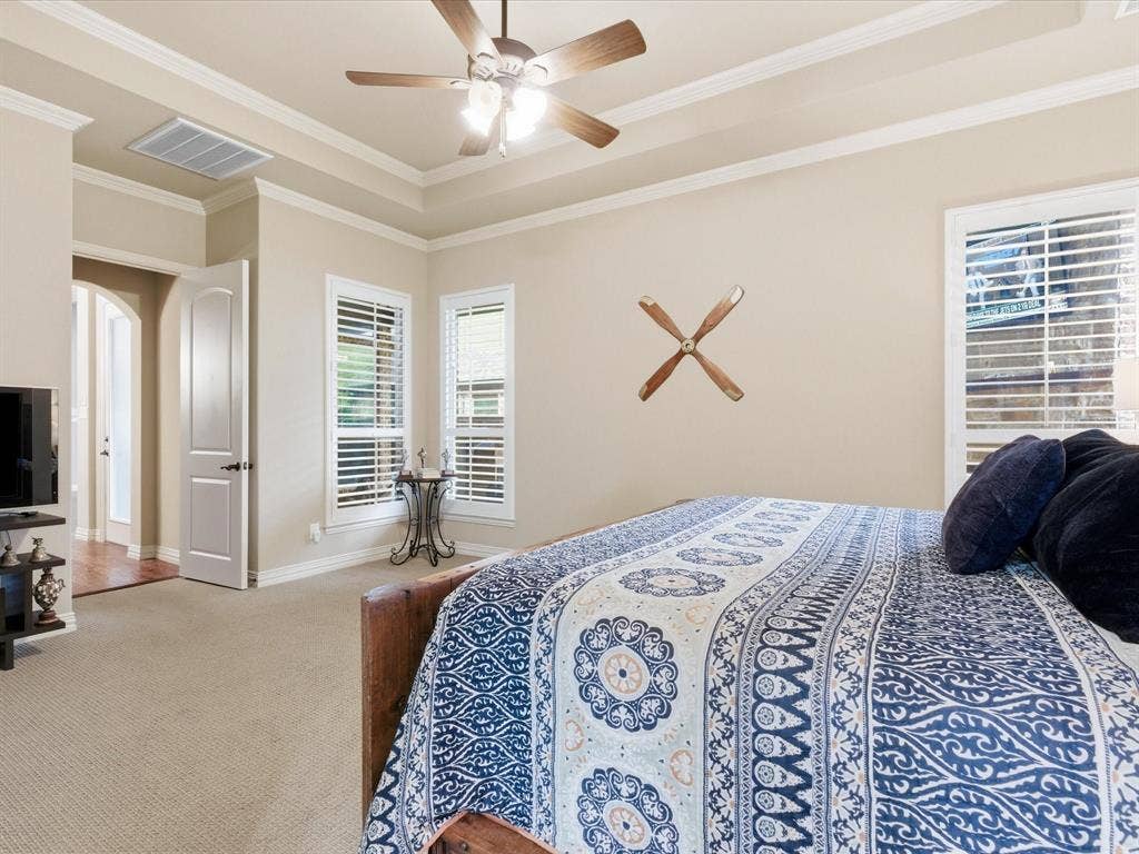2115 N Hill Drive, Irving, TX 75038 Bedroom featuring light colored carpet, ornamental molding, raised ceiling with ceiling fan. All windows open to covered porch.