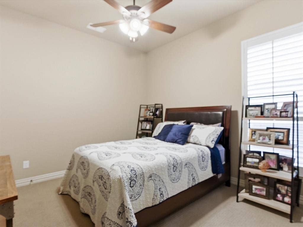 2115 N Hill Drive, Irving, TX 75038 Secondary bedroom with large walk in closet and ensuite bathroom. Window with plantation shutters provides good natural light.