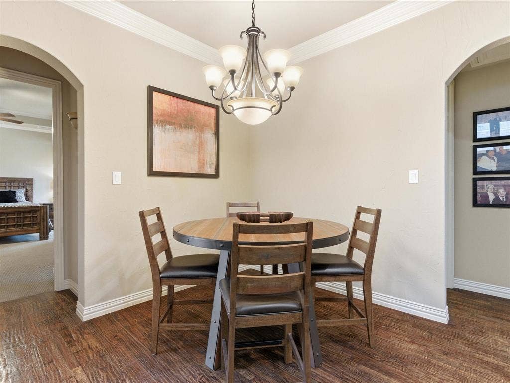 2115 N Hill Drive, Irving, TX 75038 Dining with wide arched walkways, ornamental molding, oak wood floors, and hanging light.
