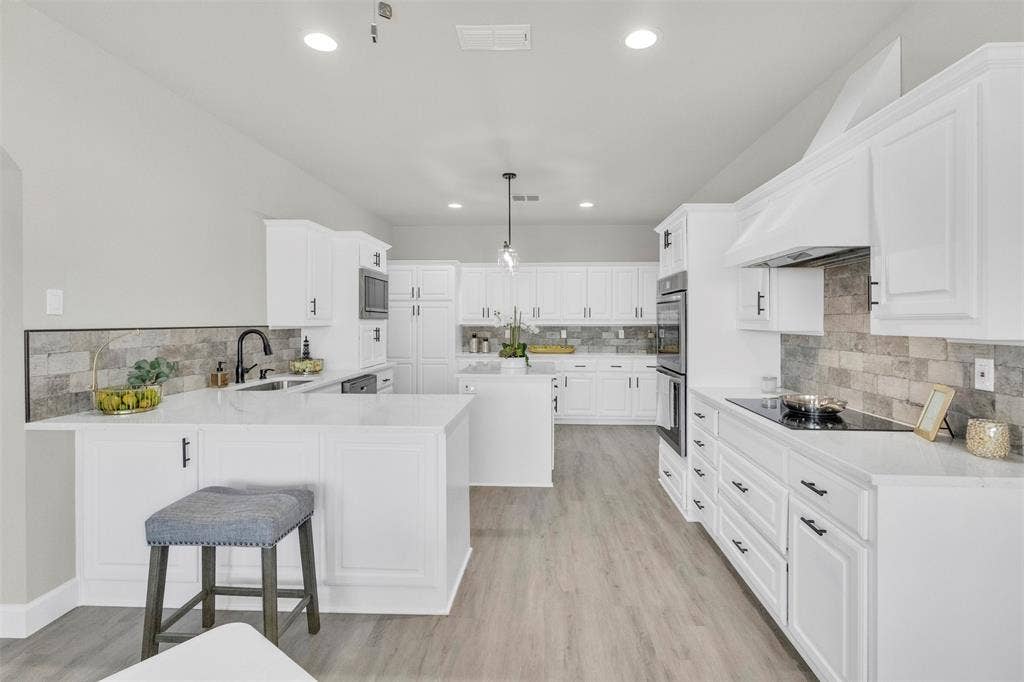 3415 Fm 3211, Caddo Mills, TX 75135 Kitchen featuring a peninsula, a breakfast bar, white cabinetry, a center island, and light stone counters