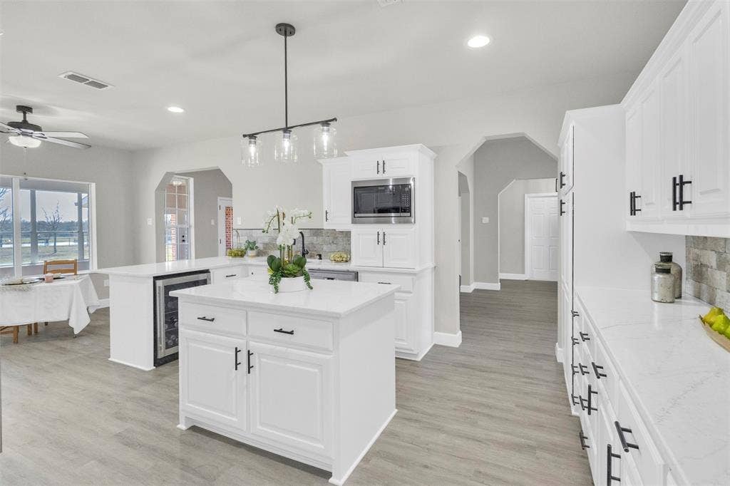 3415 Fm 3211, Caddo Mills, TX 75135 Kitchen with arched walkways, a peninsula, a center island, backsplash, and beverage cooler