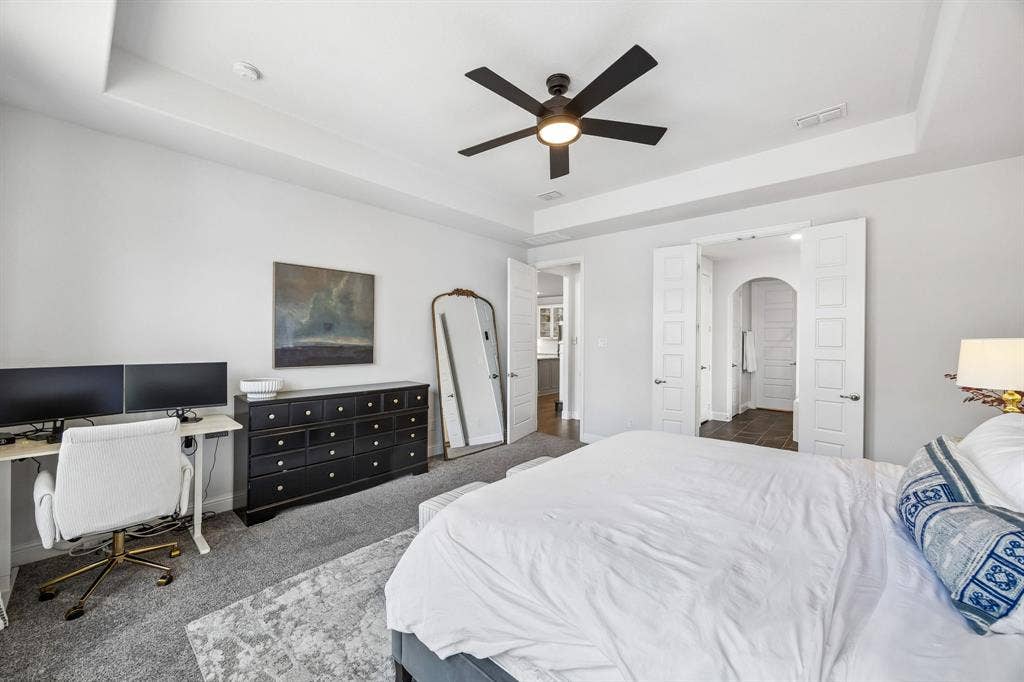 13674 Carmenita Drive, Frisco, TX 75035 Bedroom featuring a tray ceiling, dark colored carpet, ceiling fan, a desk, and arched walkways