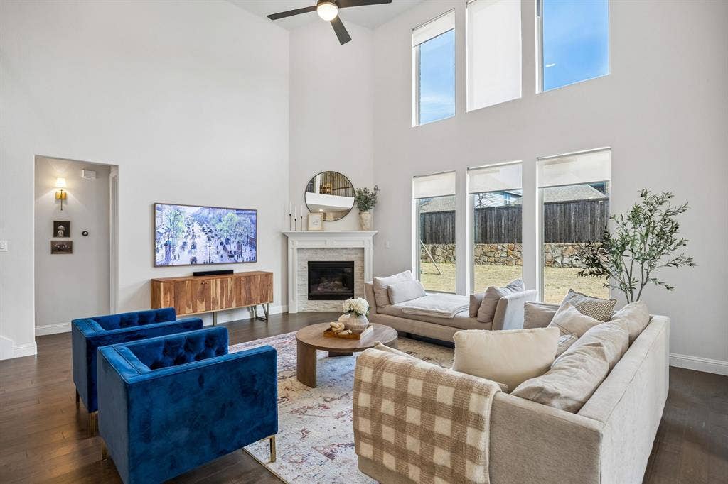 13674 Carmenita Drive, Frisco, TX 75035 Living room with dark wood finished floors, healthy amount of natural light, a stone fireplace, and a high ceiling