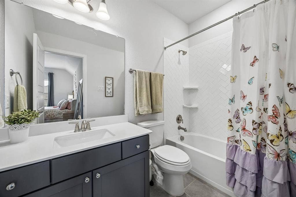 13674 Carmenita Drive, Frisco, TX 75035 Full bathroom with vanity, shower / bathtub combination with curtain, ensuite bathroom, and dark tile patterned floors