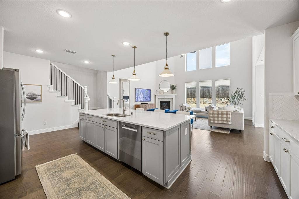 13674 Carmenita Drive, Frisco, TX 75035 Kitchen with open floor plan, a fireplace, stainless steel appliances, gray cabinetry, and dark wood-style flooring