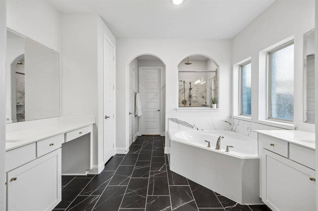 13674 Carmenita Drive, Frisco, TX 75035 Full bathroom featuring two vanities, a garden tub, a marble finish shower, and dark marble finish floors. Walk-in Closet is connected to Utility room