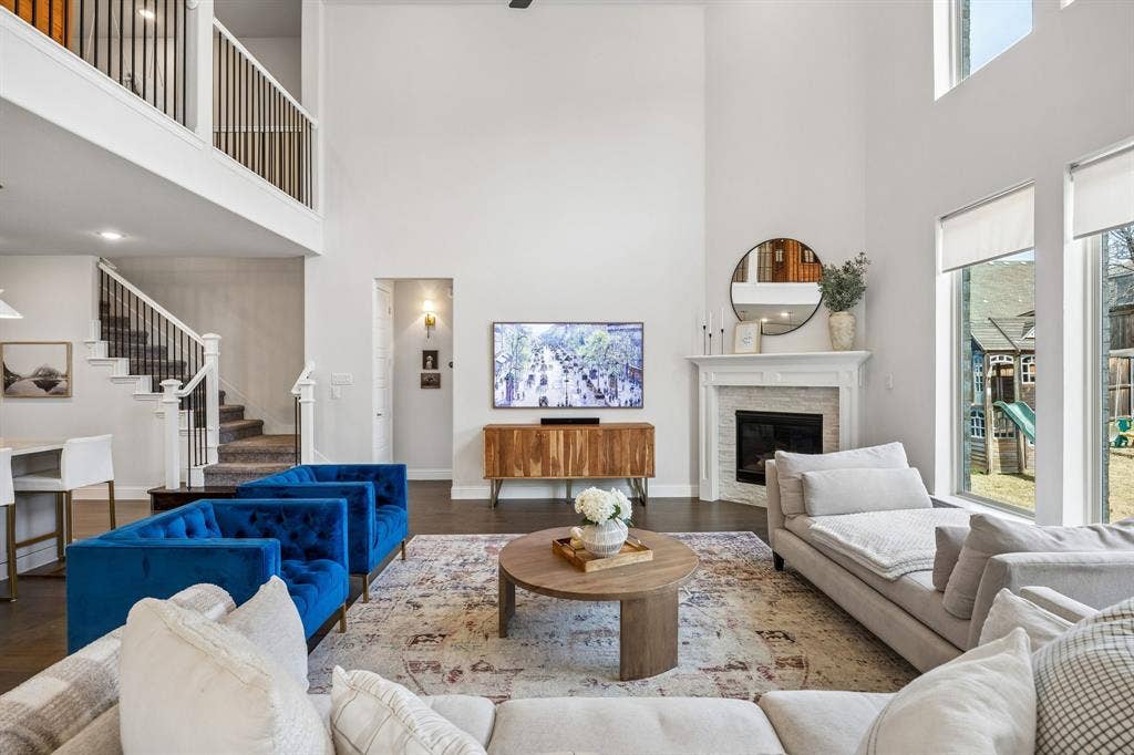 13674 Carmenita Drive, Frisco, TX 75035 Living area featuring wood finished floors, a stone fireplace, and a high ceiling