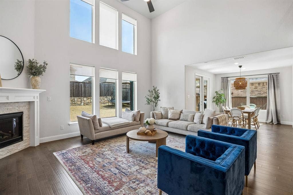 13674 Carmenita Drive, Frisco, TX 75035 Living area featuring dark wood-style floors, a brick fireplace, a ceiling fan, and a high ceiling