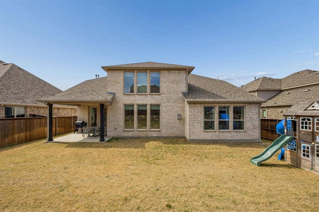 13674 Carmenita Drive, Frisco, TX 75035 Rear view of house with a patio area, roof with shingles, a fenced backyard, brick siding, and a playground