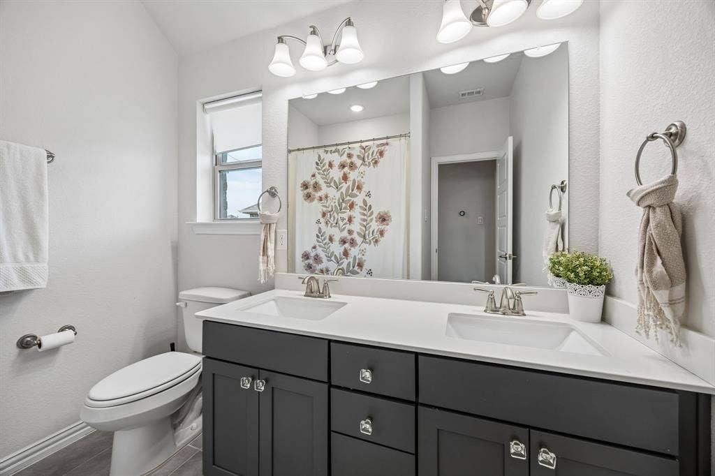 13674 Carmenita Drive, Frisco, TX 75035 Bathroom with double vanity, a shower with shower curtain, and a textured wall