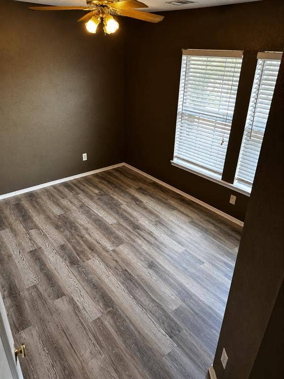 103 Denali Court, Terrell, TX 75160 Room featuring wood-finish flooring, two large windows with blinds, a ceiling fan with integrated lighting, and dark-toned walls