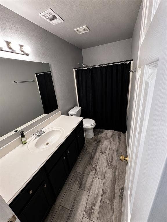 103 Denali Court, Terrell, TX 75160 Bathroom featuring a white sink vanity with dark cabinetry, wood-finish flooring, and a shower with a black curtain