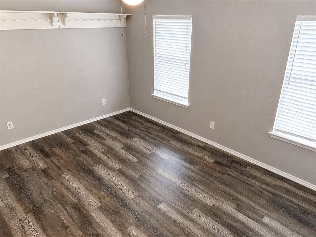 103 Denali Court, Terrell, TX 75160 Room featuring wood-finish flooring, light grey walls, white baseboards, and two windows with blinds