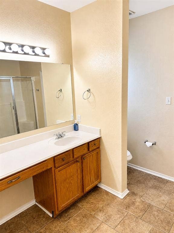 103 Denali Court, Terrell, TX 75160 Primary Bathroom featuring a vanity with a white countertop and integrated sink, a large mirror, and a chrome light fixture