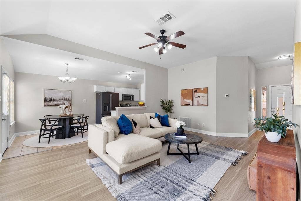 2408 Castle Ridge Drive, McKinney, TX 75071 Virtually staged. Living area with light wood finished floors, ceiling fan, a chandelier, and lofted ceiling