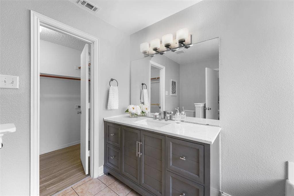 2408 Castle Ridge Drive, McKinney, TX 75071 Bathroom featuring vanity, light tile patterned floors, a walk in closet, and a textured wall