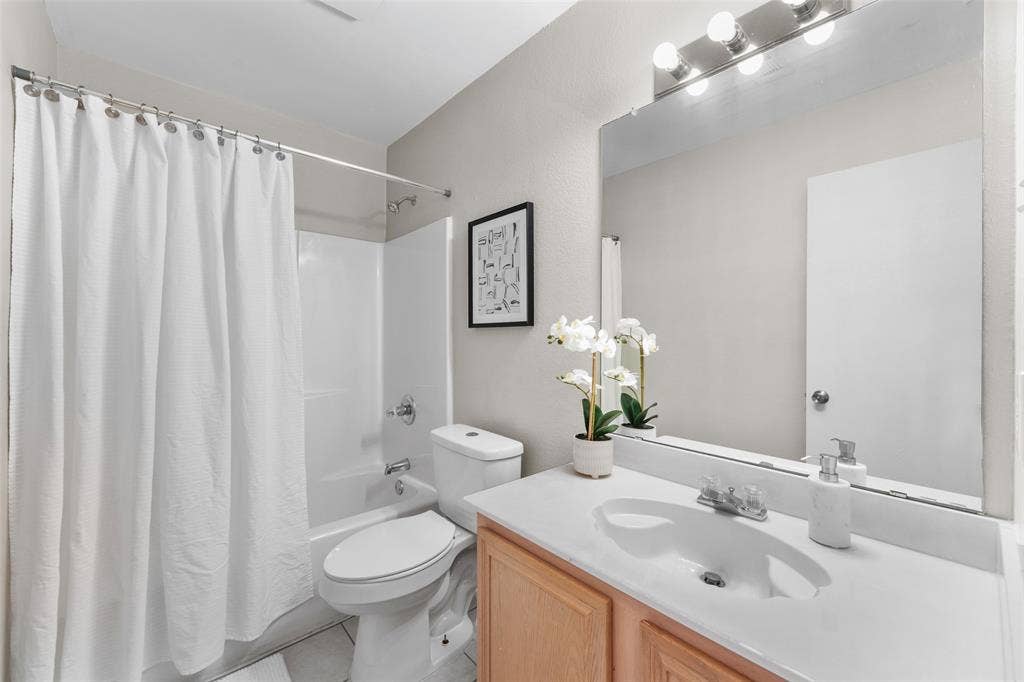 2408 Castle Ridge Drive, McKinney, TX 75071 Bathroom featuring vanity, shower / bathtub combination with curtain, and light tile patterned flooring