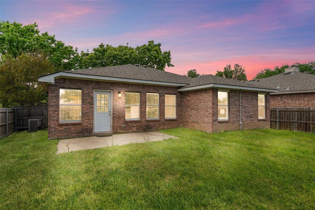 2408 Castle Ridge Drive, McKinney, TX 75071 Back of property at dusk featuring a fenced backyard, brick siding, a patio, and roof with shingles
