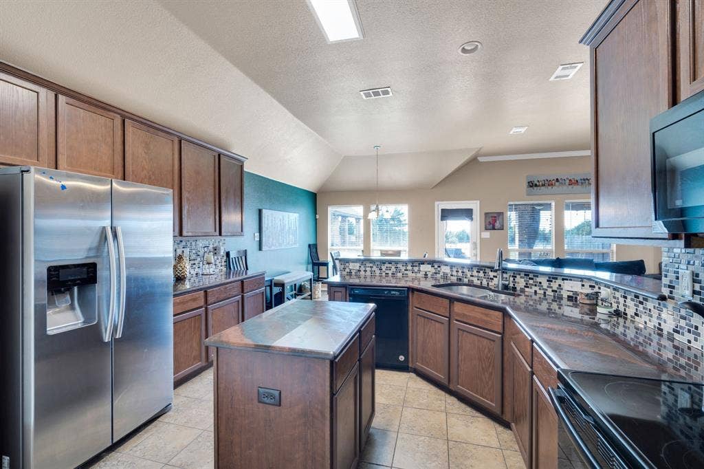 160 Berkshire Lane, Waxahachie, TX 75165 Kitchen featuring black appliances, backsplash, a peninsula, a center island, and dark countertops
