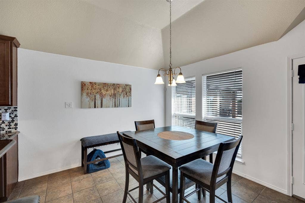 160 Berkshire Lane, Waxahachie, TX 75165 Vaulted ceiling dining area featuring tile flooring, a multi-light chandelier, and two windows with blinds