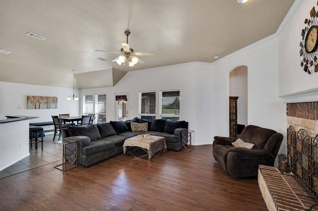 160 Berkshire Lane, Waxahachie, TX 75165 Spacious living area featuring wood-finish flooring, a ceiling fan, and a fireplace with brick and decorative tile accents