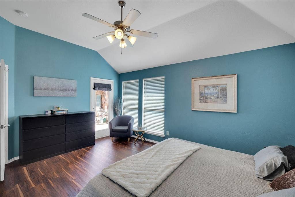 160 Berkshire Lane, Waxahachie, TX 75165 Vaulted ceiling bedroom featuring wood-finish flooring, two windows with blinds, and a built-in ceiling fan with light fixture