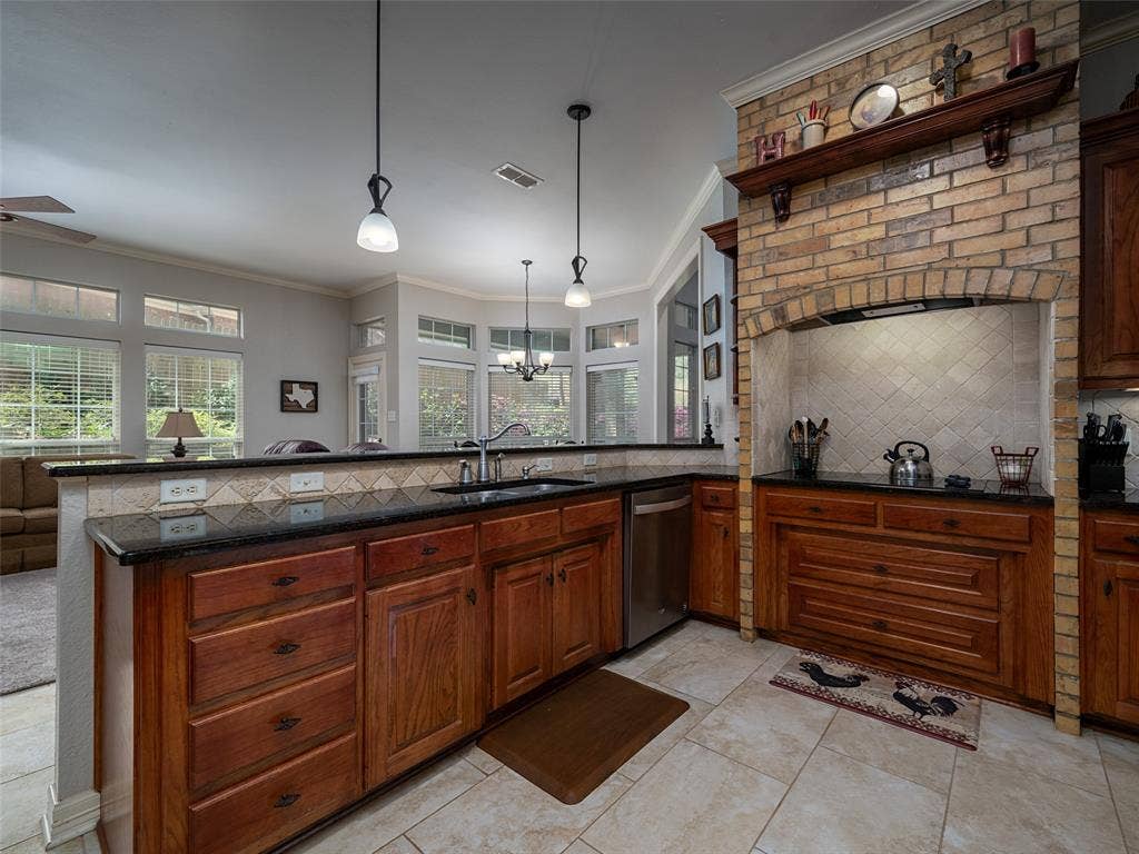 1137 Ashwood Drive, Tyler, TX 75703 Brick surround on the cooktop, gorgeous stained wood cabinets, and granite counter tops with adorable backsplash make this kitchen a dream come true.