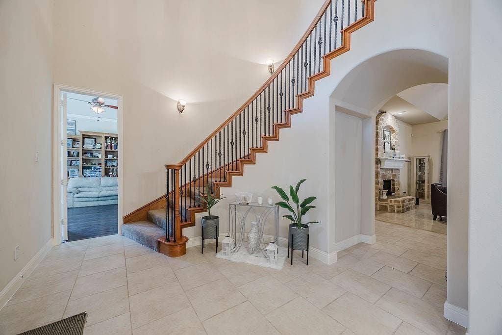 1011 Parview Circle, Grand Prairie, TX 75104 Stairs with a high ceiling, arched walkways, a ceiling fan, a stone fireplace, and tile patterned floors