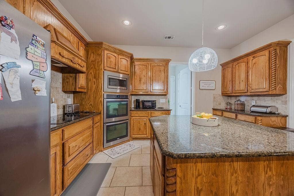 1011 Parview Circle, Grand Prairie, TX 75104 Kitchen with stainless steel appliances, dark granite countertops, tasteful backsplash, and wood finish cabinetry