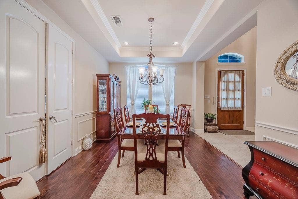 1011 Parview Circle, Grand Prairie, TX 75104 Dining area featuring dark wood-style floors, a tray ceiling, a chandelier, and ornamental molding