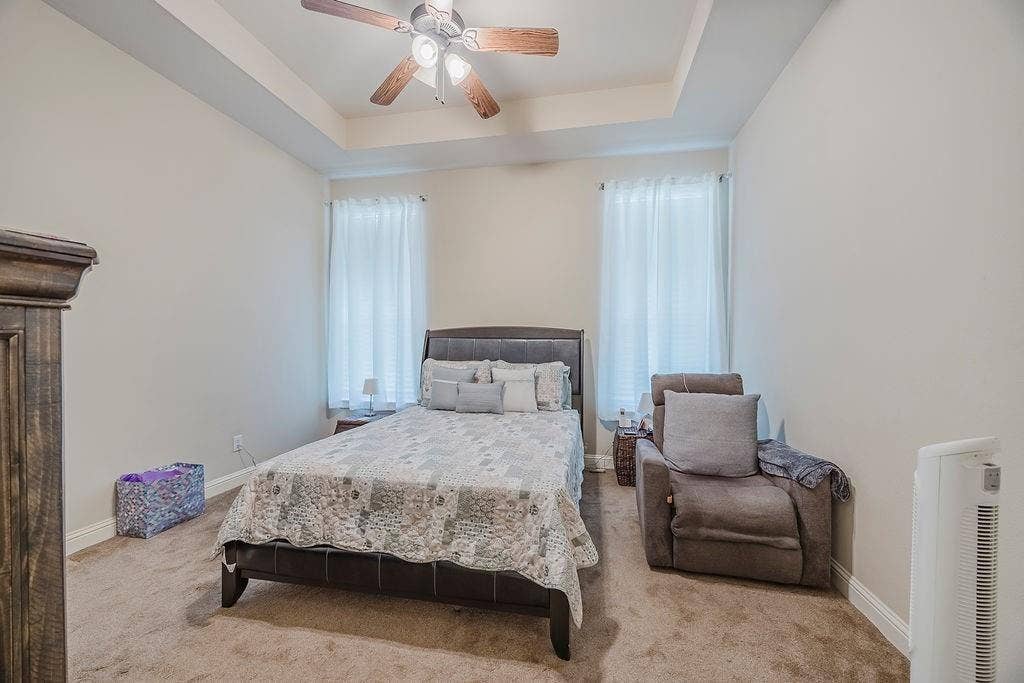 1011 Parview Circle, Grand Prairie, TX 75104 Bedroom with a tray ceiling, carpet flooring, a ceiling fan, and multiple windows