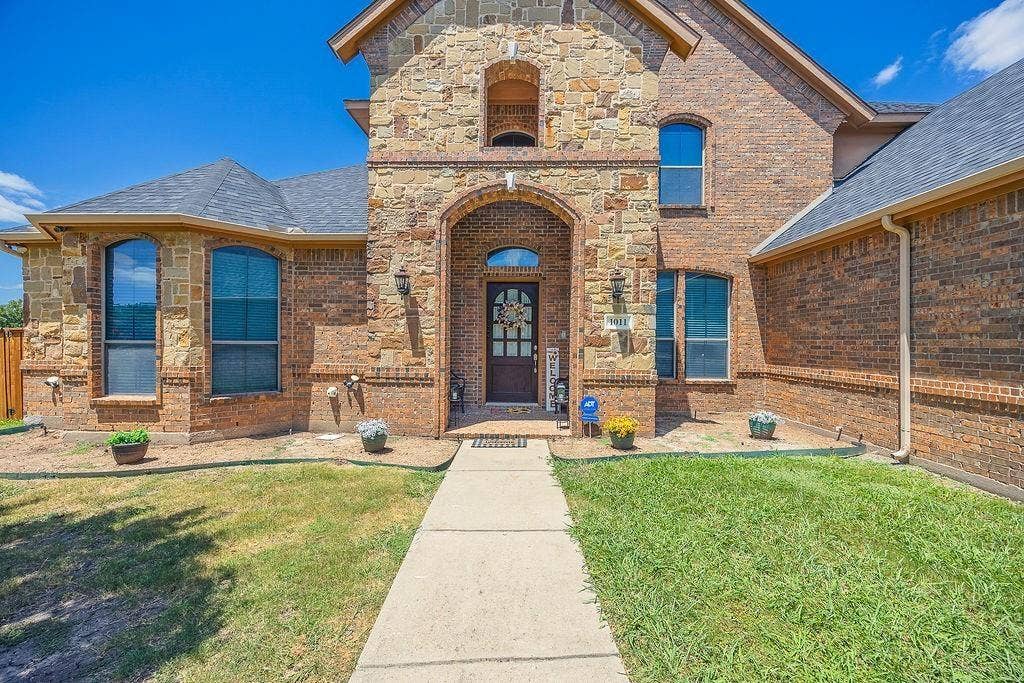 1011 Parview Circle, Grand Prairie, TX 75104 Doorway to property with a yard, brick siding, and stone siding